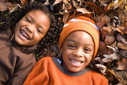 A pair of young children playing in a pile of leaves